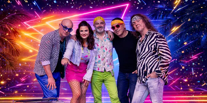 Five band members pose together against a colorful neon backdrop with palm trees and fireworks. They wear bright, retro-style clothing, including patterned shirts, sunglasses, bandanas, pink pants, and green pants. Five band members pose together against a colorful neon backdrop with palm trees and fireworks. They wear bright, retro-style clothing, including patterned shirts, sunglasses, bandanas, pink pants, and green pants.